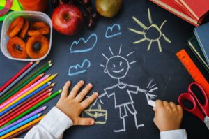 childrens hands writing on a blackboard