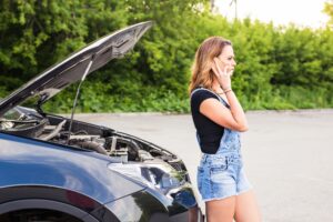 young woman with broken down car with hood open call for help